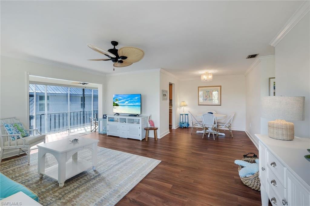 Open-concept living space featuring wood-finish flooring, white walls, and crown molding