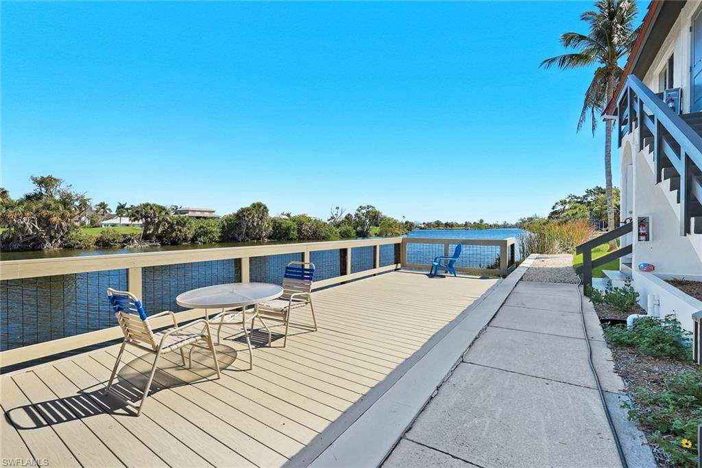 Waterfront deck featuring a composite surface, white railing with mesh infill, and a palm tree