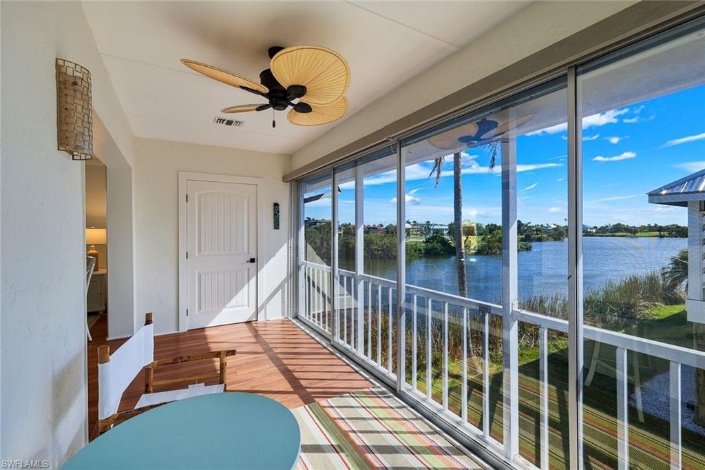 Screened lanai featuring wood-finish flooring, a ceiling fan, and a wall-mounted light fixture
