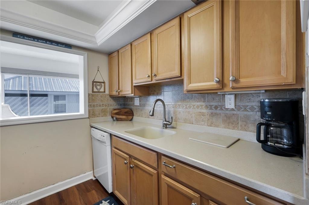 Kitchen area featuring wood-finish cabinetry with silver-tone hardware, a light-toned countertop, and a tiled backsplash