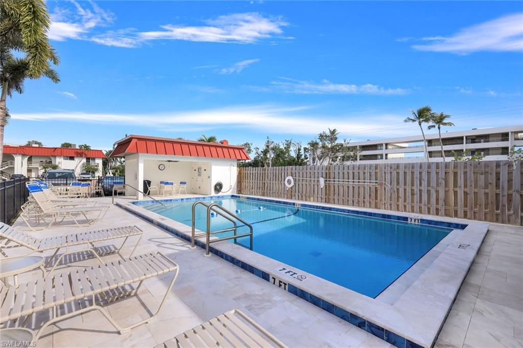 Rectangular swimming pool with blue tile accents, surrounded by a light-toned paved deck