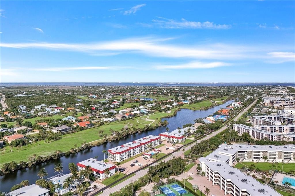 Waterfront community featuring multiple buildings, manicured grounds, and tennis courts