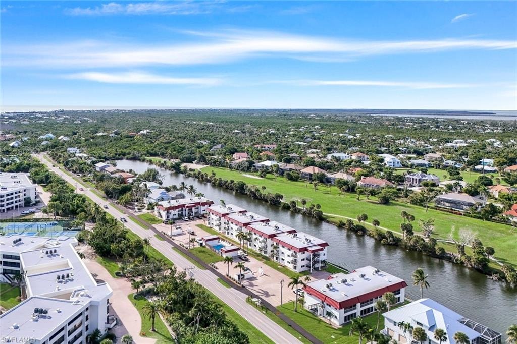 Aerial perspective featuring waterfront properties, a manicured golf course, and a distant ocean horizon
