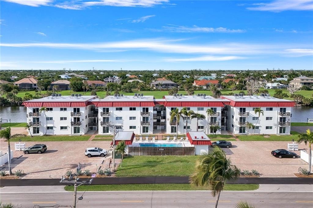 Waterfront condominium complex featuring multiple balconies, a red metal roof, and an outdoor swimming pool