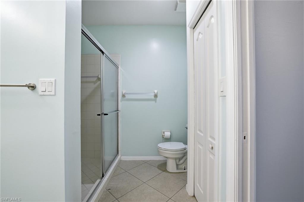 Primary Bathroom with light tile patterned floors, a stall shower, and a closet