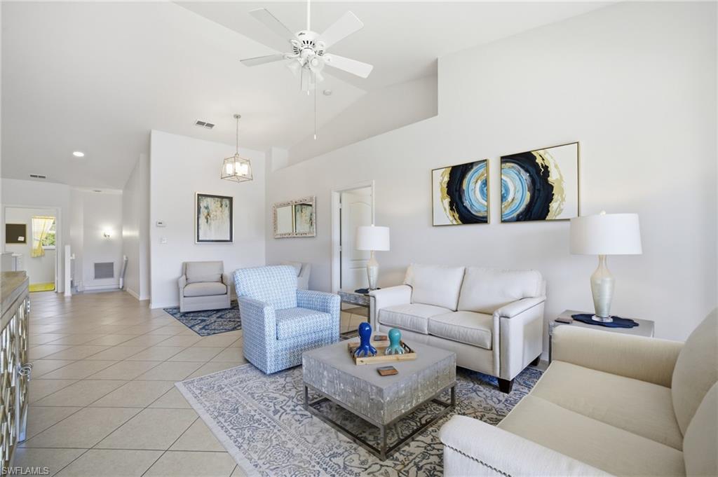 Living area featuring light tile patterned floors, a ceiling fan, and high vaulted ceiling with lake view