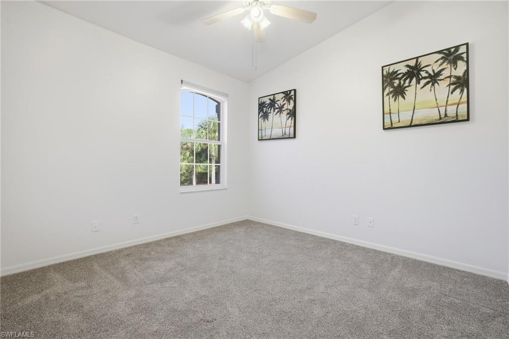 Guest bedroom featuring vaulted ceiling, carpet floors, and a ceiling fa