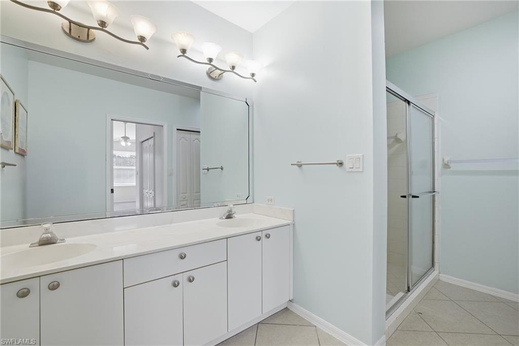 Primary bathroom featuring light tile patterned floors, a stall shower, and double vanity