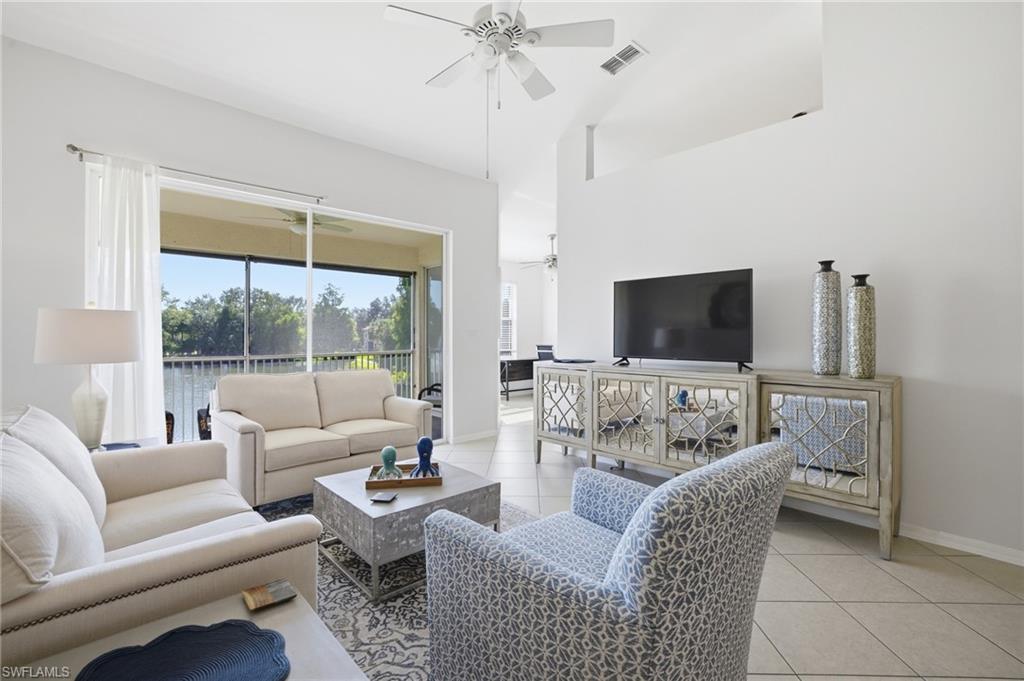 Living area featuring light tile patterned floors, a ceiling fan, and high vaulted ceiling with lake view