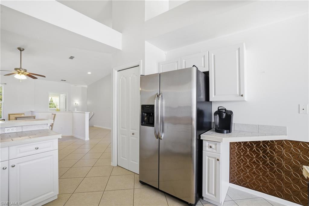 Kitchen featuring stainless steel fridge with ice dispenser, white cabinets