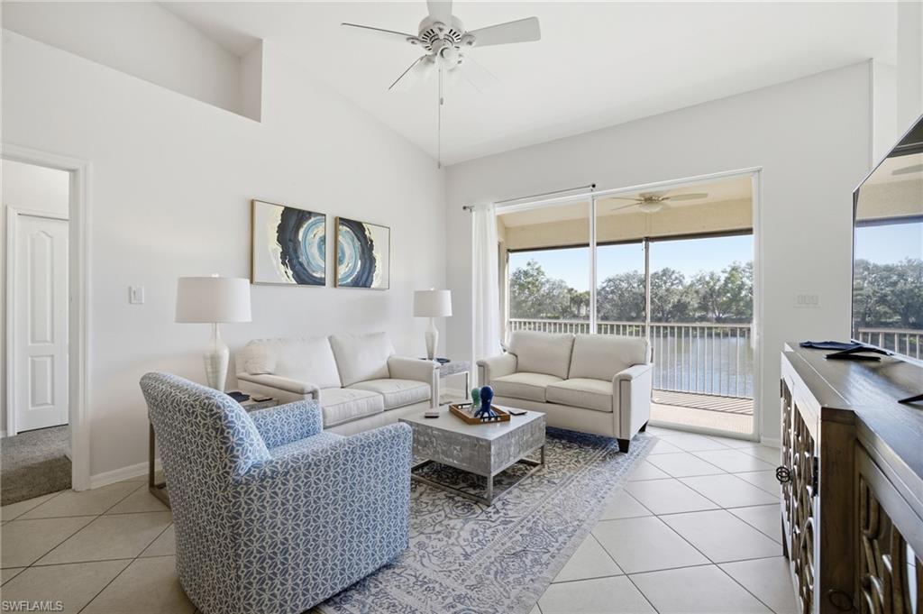 Living area featuring light tile patterned floors, a ceiling fan, and high vaulted ceiling with lake view