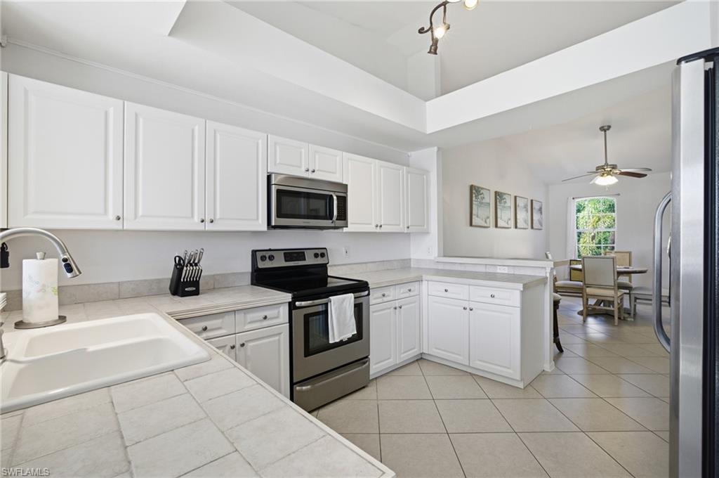 Kitchen featuring stainless steel appliances, white cabinets, tile countertops