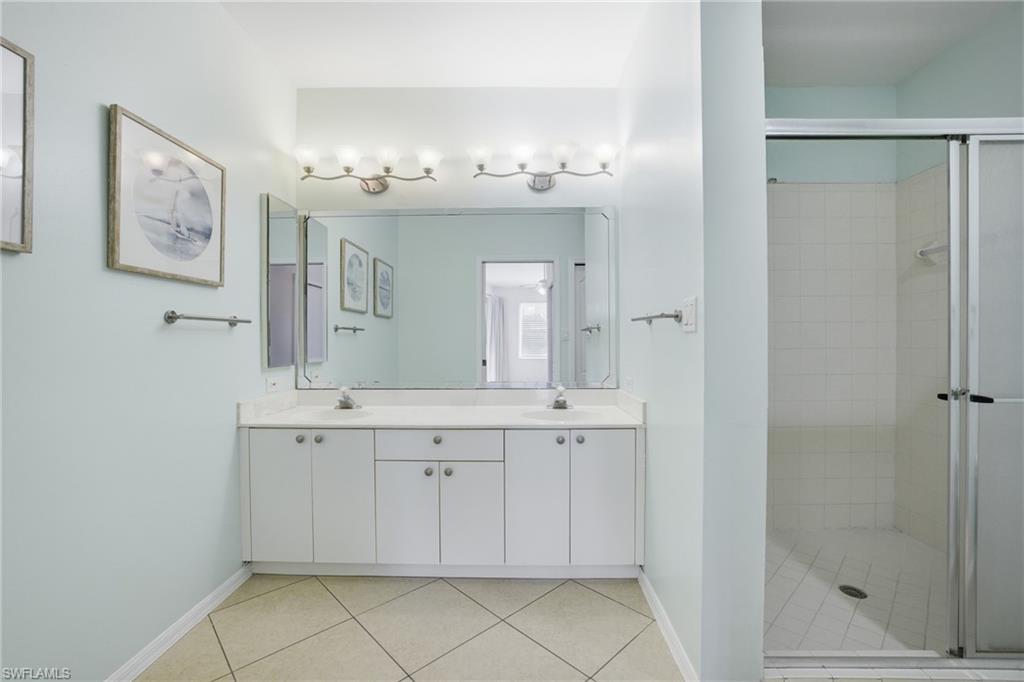 Primary Bathroom with a stall shower, double vanity, and light tile patterned floors