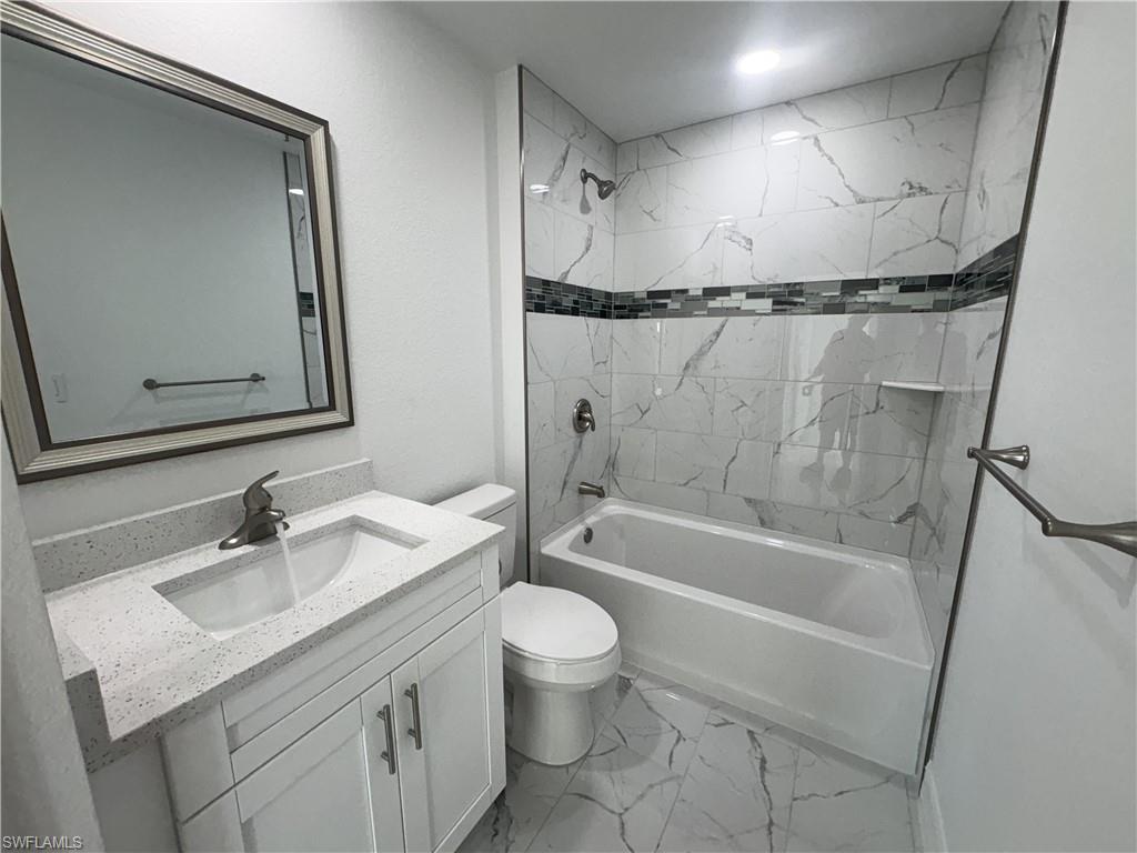 Full bathroom featuring a white vanity with a light speckled countertop and undermount sink
