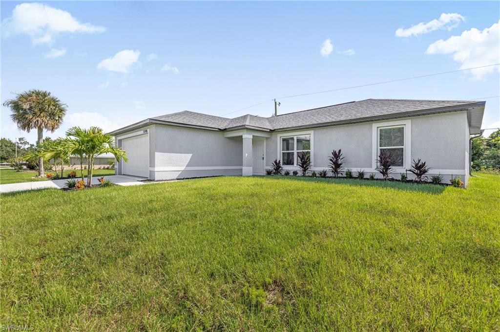 Contemporary stucco exterior with an attached garage, landscaped foundation plantings, a concrete driveway, and a paved walkway