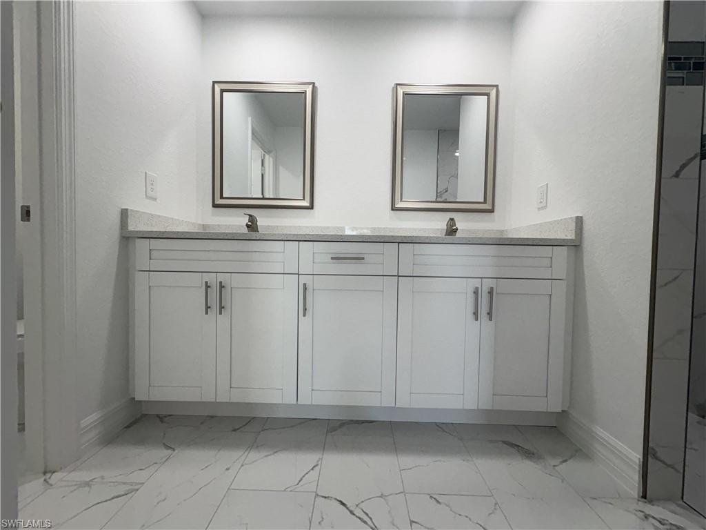 Double vanity with white shaker cabinetry, quartz countertops, and dual framed mirrors