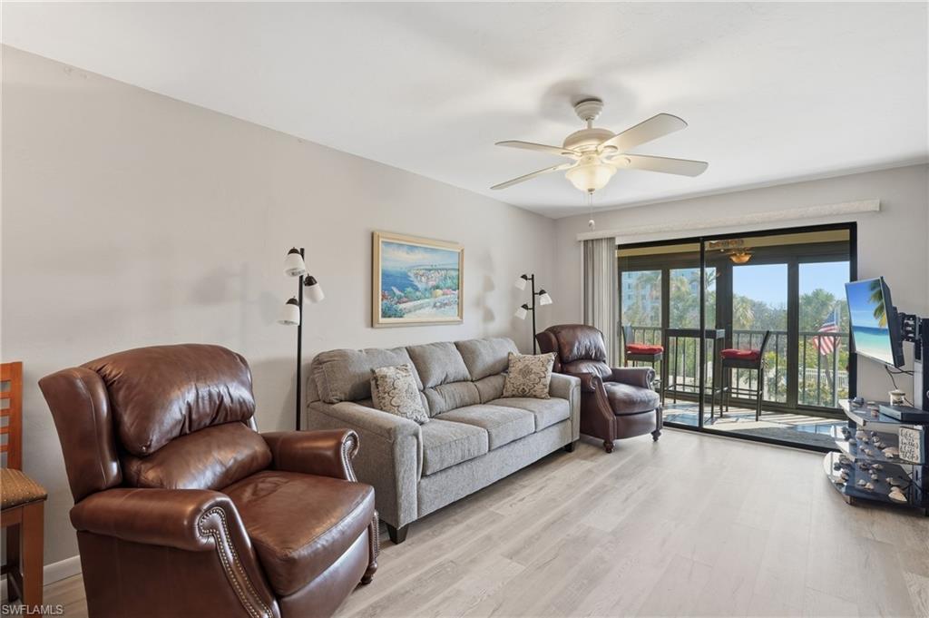 Bright living area featuring light wood-finish flooring and a ceiling fan - Virtually Edited Image