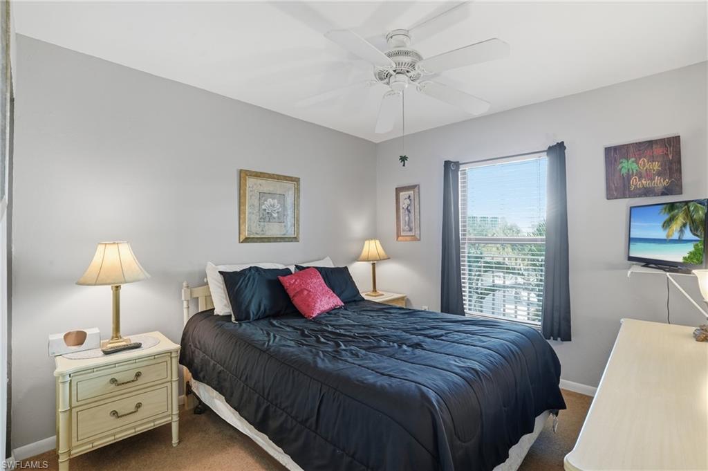 Bedroom featuring a ceiling fan, wall-mounted television, and a window with blinds and dark curtains - Virtually Edited Image