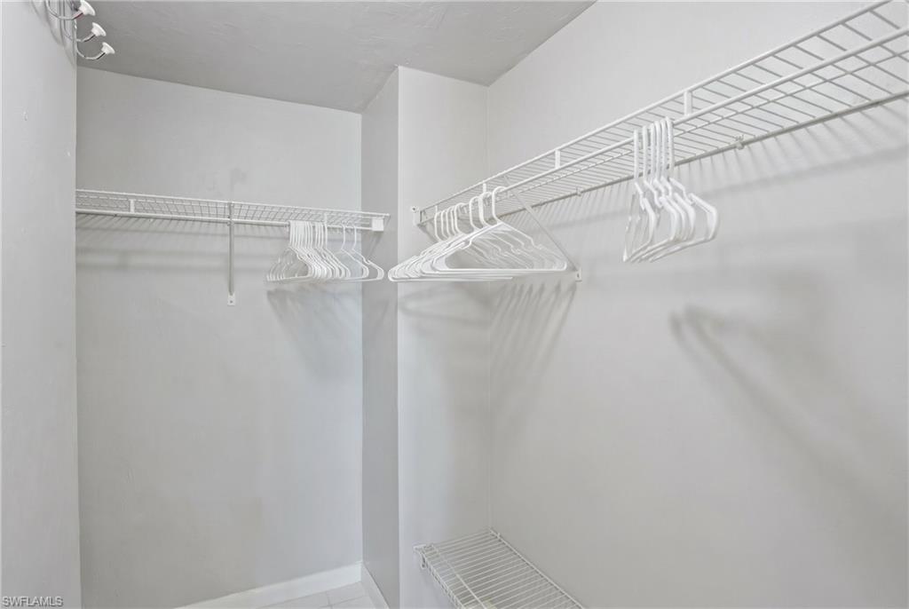 Primary Walk-in closet featuring white wire shelving and hanging rods - Virtually Edited Image