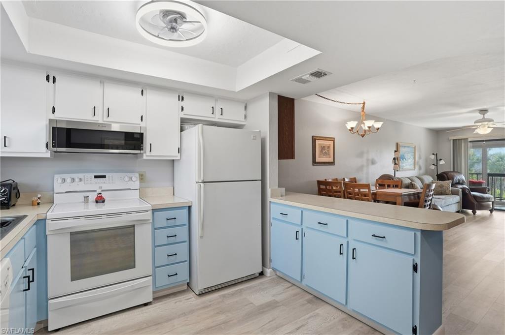 Kitchen featuring white upper cabinetry, light blue lower cabinetry, and a countertop extending into a breakfast bar - Virtually Edited Image