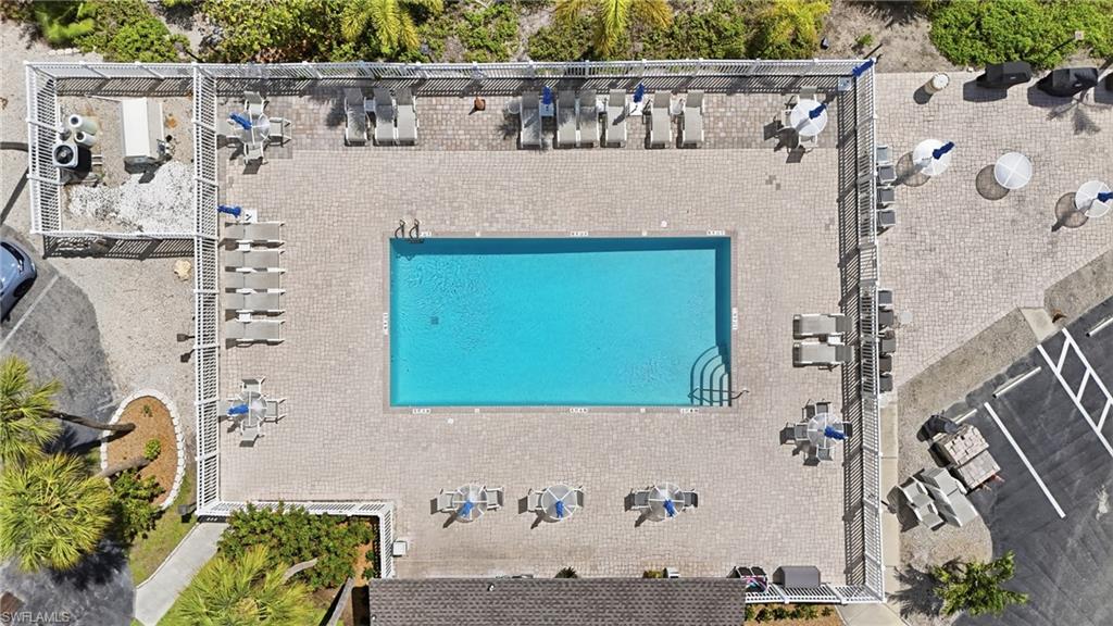 Resort-style pool area featuring a rectangular pool, extensive paver decking, and perimeter fencing - Virtually Edited Image