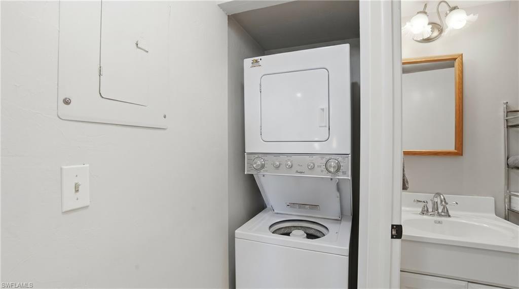 Stackable washer and dryer unit, white vanity with integrated sink, chrome faucet, and a wall-mounted mirror with a wood frame - Virtually Edited Image