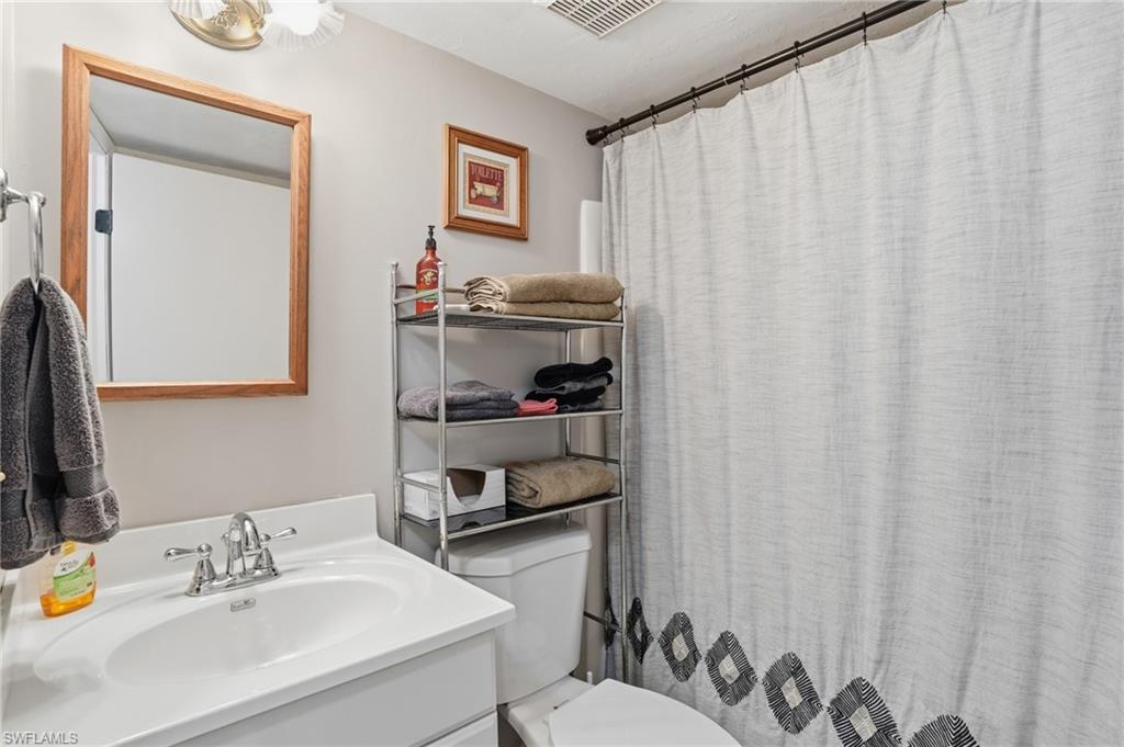 Bathroom featuring a vanity with an integrated sink, polished chrome faucet, and a large wood-framed mirror - Virtually Edited Image
