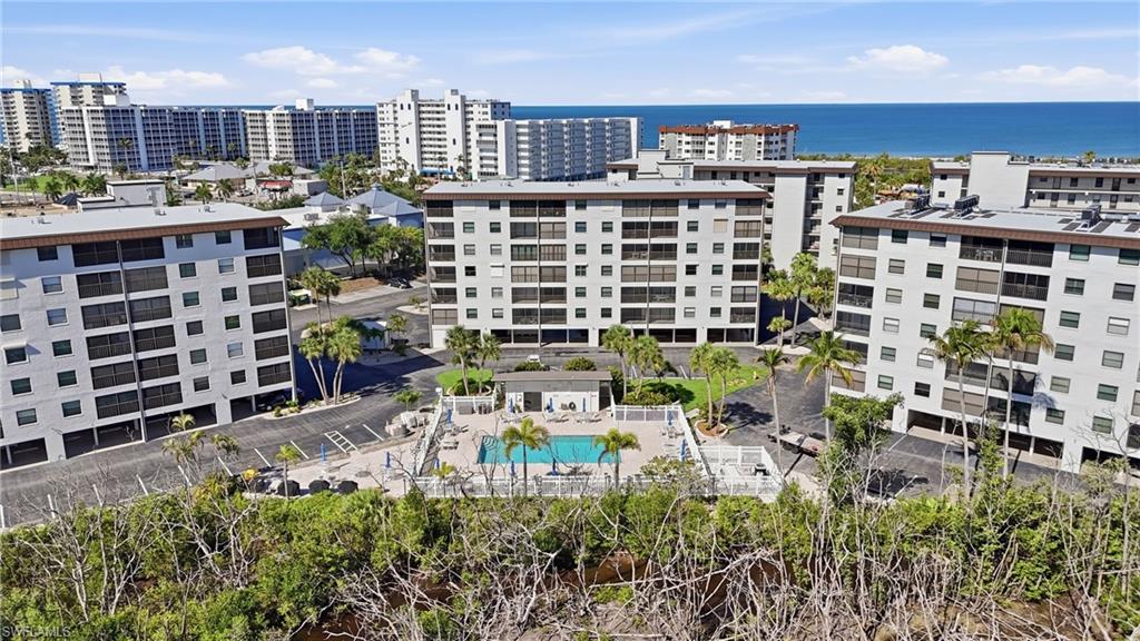 Multi-story condominium complex featuring a central swimming pool with an accompanying patio area - Virtually Edited Image