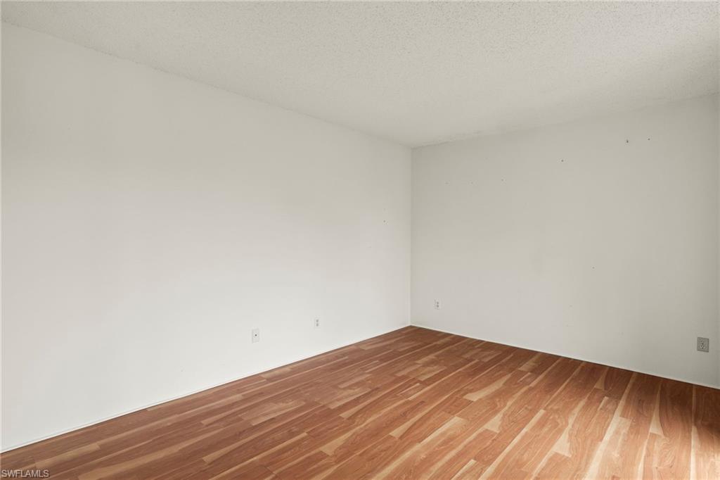 Neutral wall finishes, wood-finish flooring, and a textured ceiling