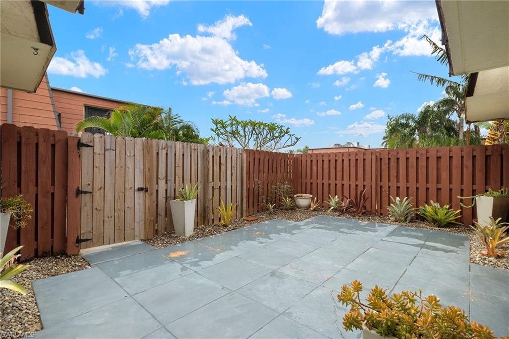 Private outdoor patio featuring large-format paver flooring, a perimeter wood fence, and a wooden gate
