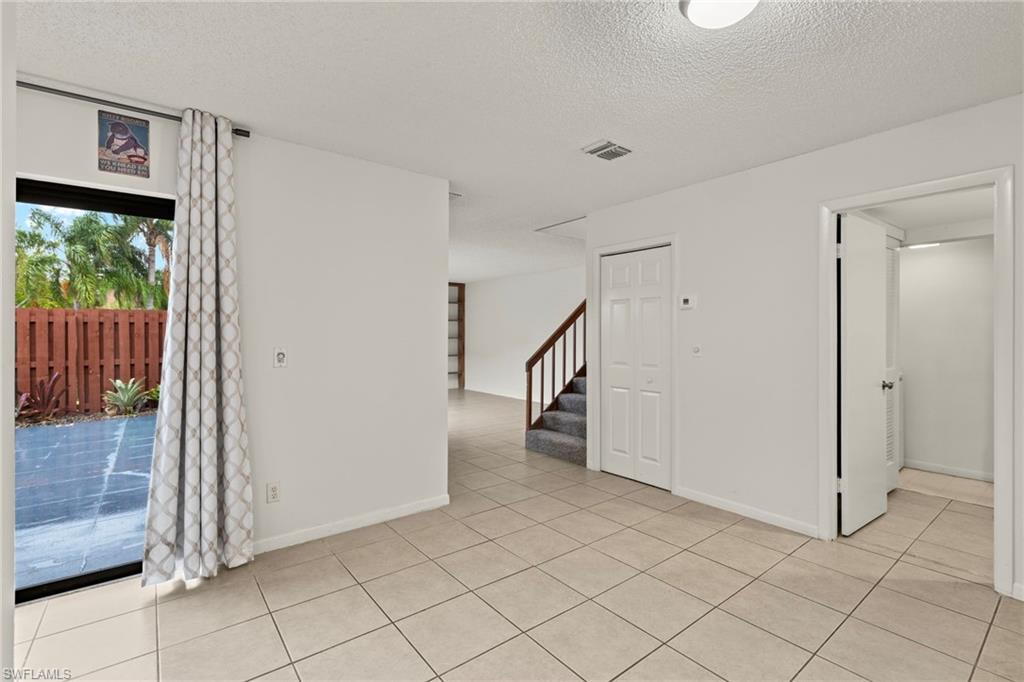 Tiled flooring extends throughout this interior space, featuring a sliding glass door opening to a private patio area