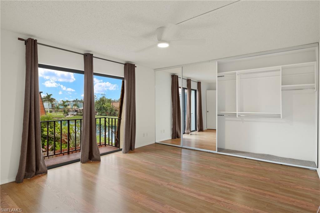 Spacious room with wood-finish flooring, a ceiling fan, and a built-in wardrobe featuring mirrored sliding doors and integrated shelving