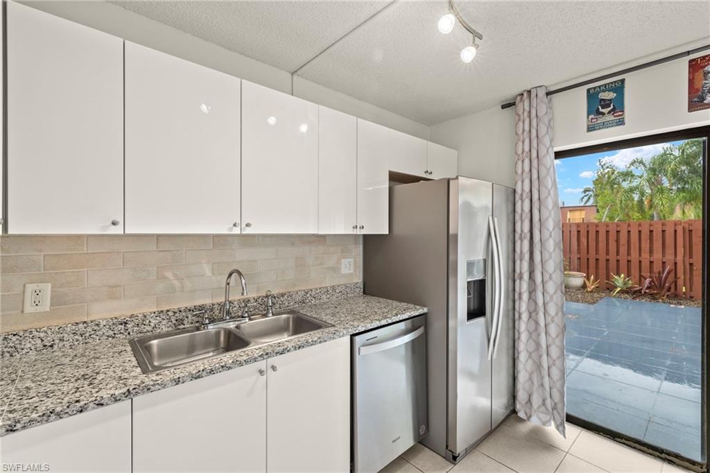 Modern kitchen featuring white cabinetry and light-toned backsplash