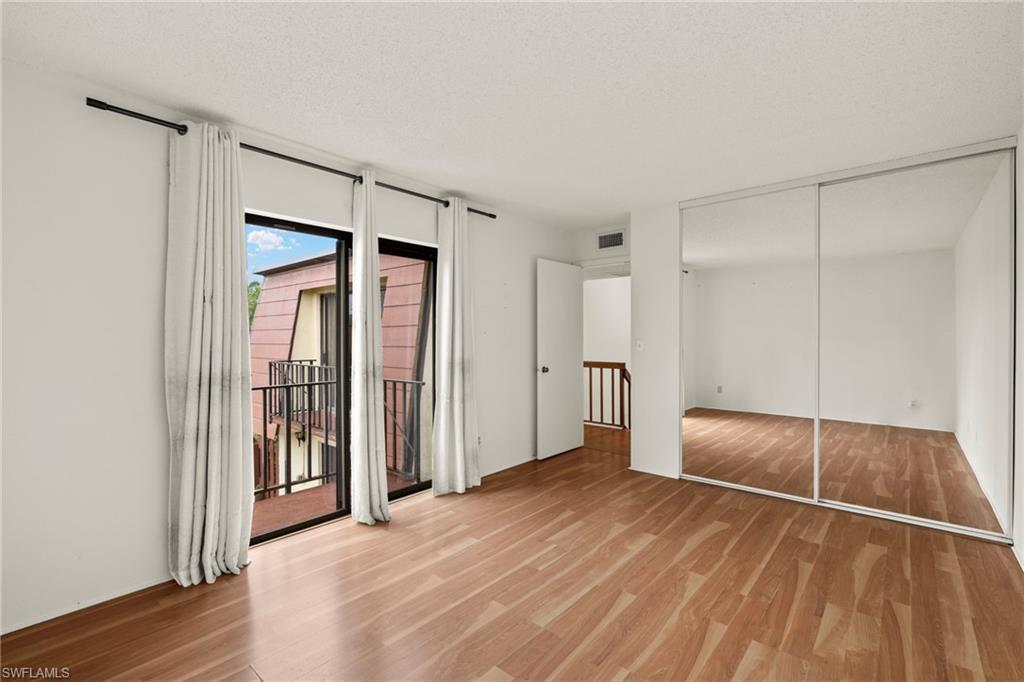 Bright interior space featuring wood-finish flooring and a full wall of mirrored sliding closet doors