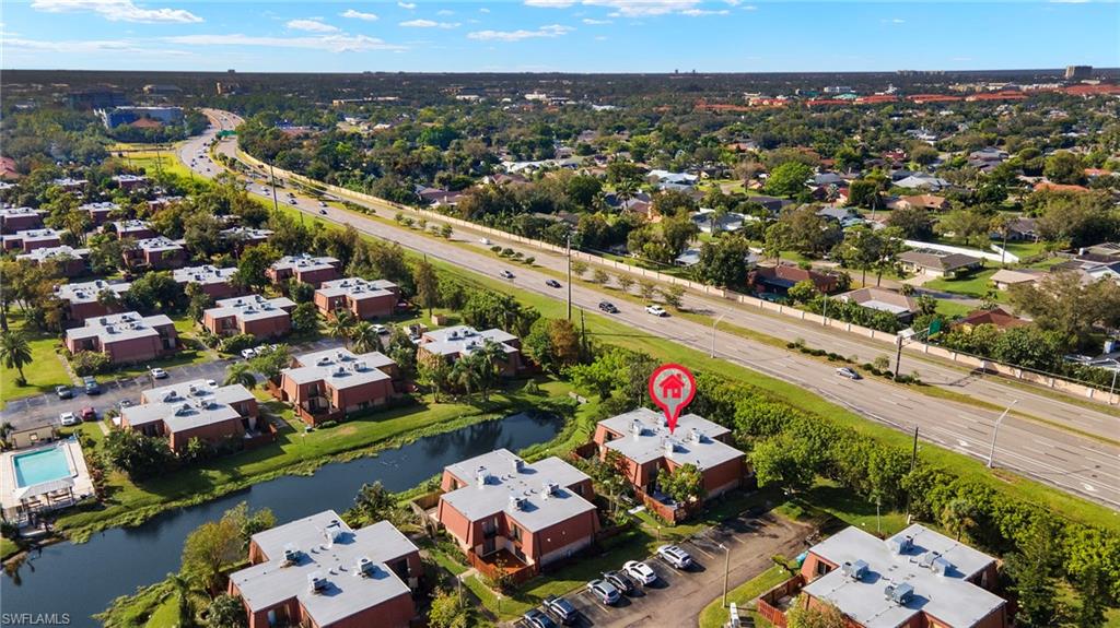 Aerial view of a multi-unit property featuring a canal, a community pool, and direct access to a multi-lane highway