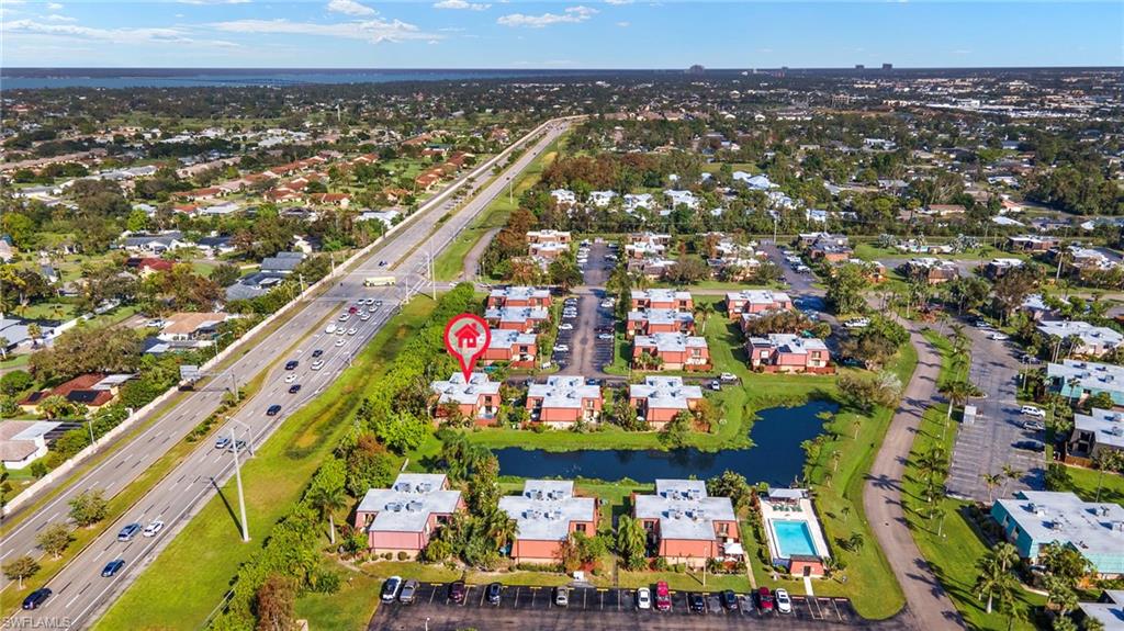 Aerial perspective showcasing a community with a central pond and multiple buildings
