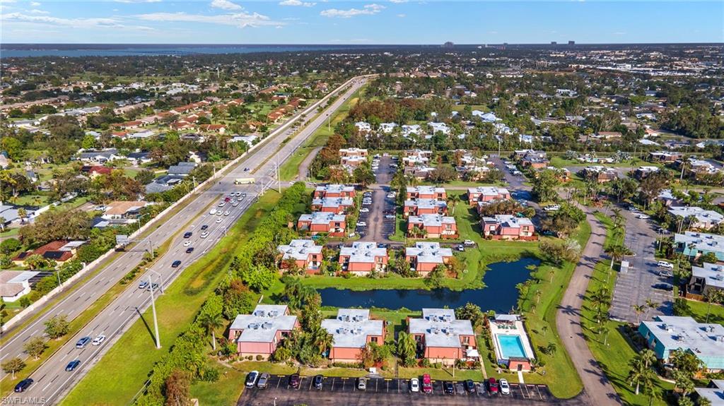 Aerial perspective showcasing a residential community with multiple buildings, a central pond, and an outdoor swimming pool