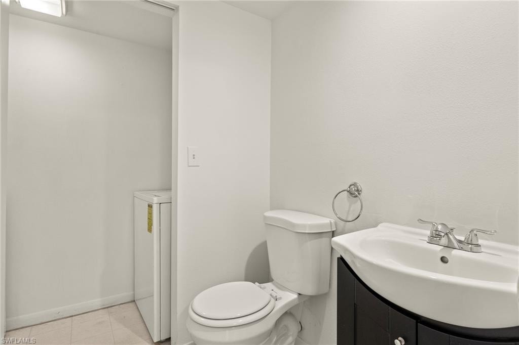 Contemporary bathroom featuring a white toilet, black vanity with an integrated white sink, and chrome fixtures