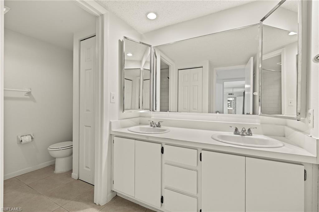 Bathroom featuring a dual vanity with integrated sinks, white cabinetry, and a mirrored medicine cabinet