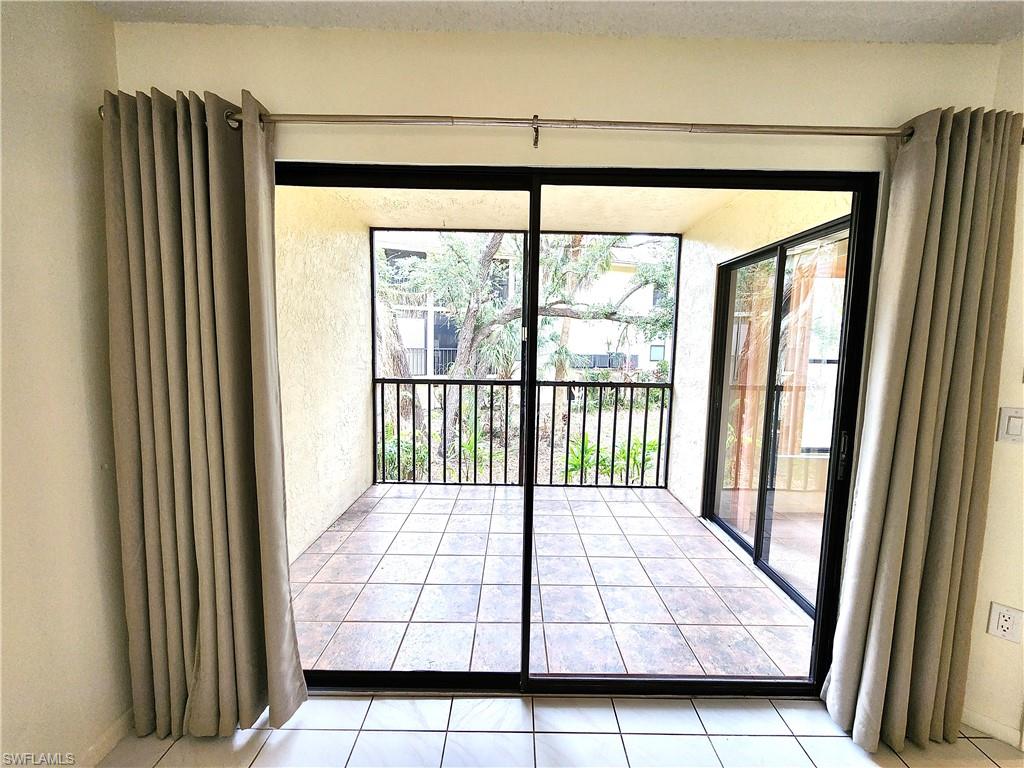 Expansive screened balcony featuring a tiled floor and black metal railing, accessed through sliding glass doors