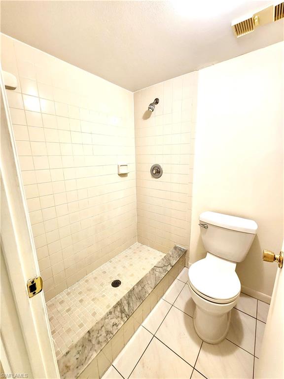 Walk-in shower with a marble-finish bench and tiled walls