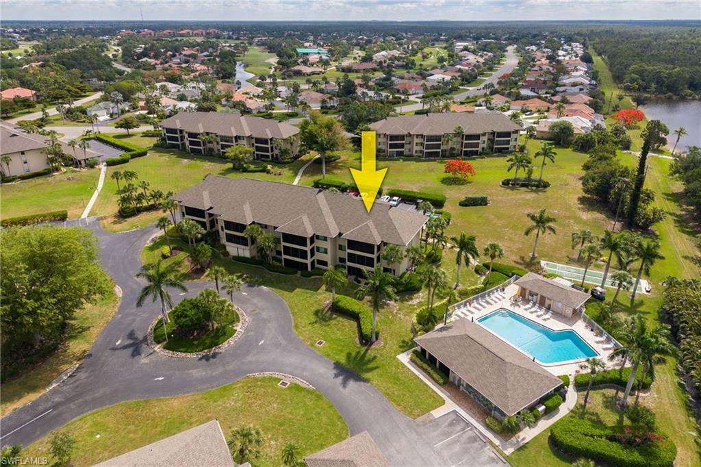 Multi-story residential building with private screened balconies, set amidst manicured green spaces and mature palm trees