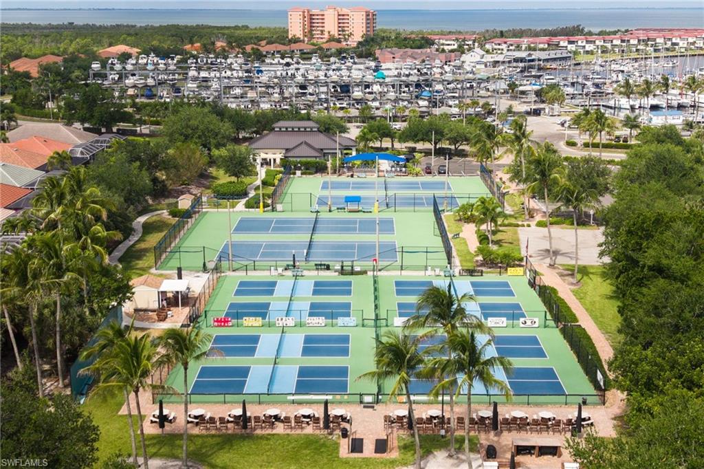 Multiple tennis courts, pickleball courts, and a clubhouse surrounded by mature palm trees