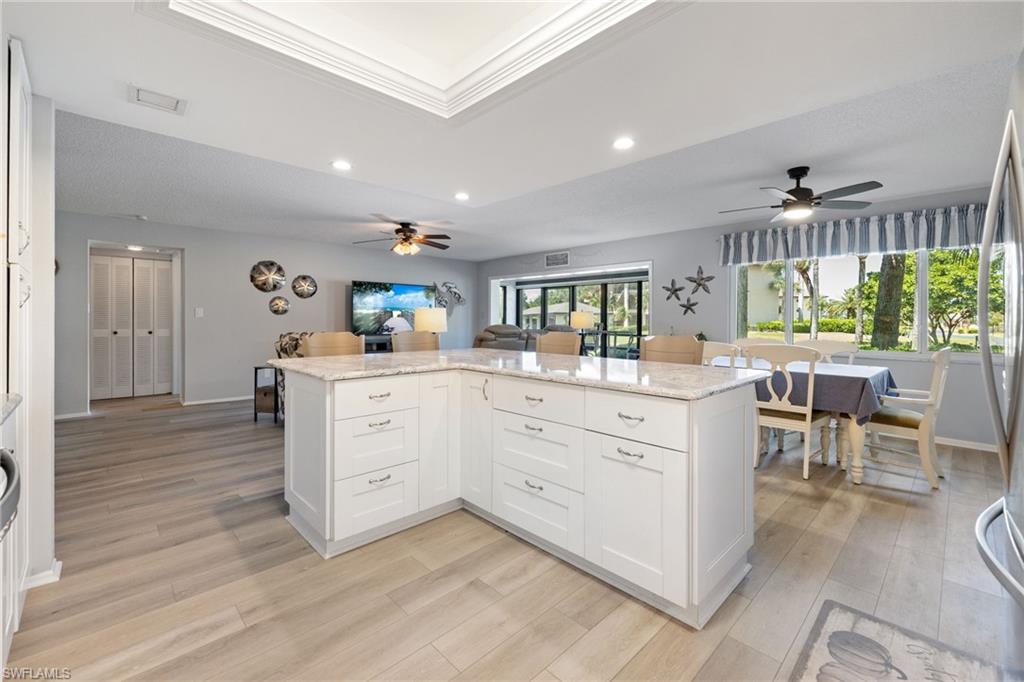 Spacious open-concept living area featuring a large kitchen island with white cabinetry and a stone countertop