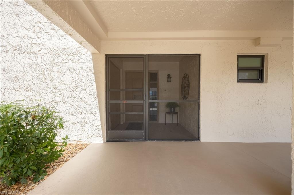 Covered entry with painted concrete flooring, textured exterior wall finish, and a screened double-door entrance