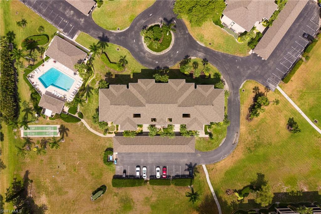Aerial panorama showcasing the property's main building, swimming pool, two bocce ball courts, and surrounding paved roadways