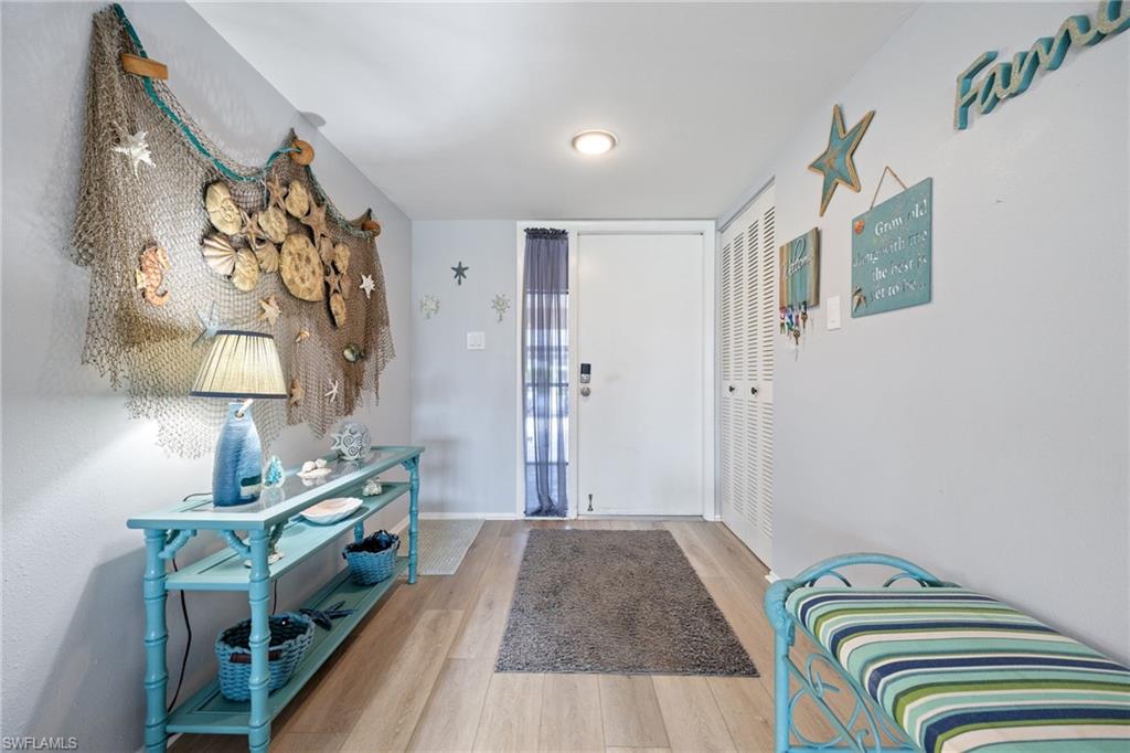 Entryway featuring light wood-finish flooring, a solid white entry door, and a built-in storage closet with louvered bifold doors