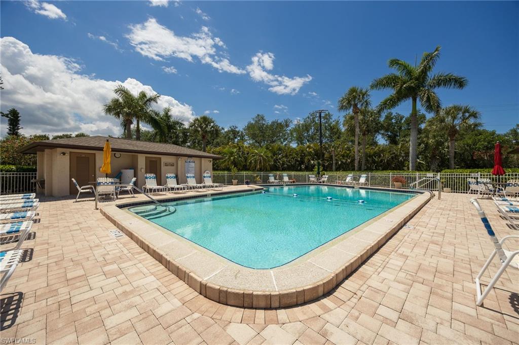 Rectangular swimming pool with integrated steps, surrounded by a paver patio and a low perimeter fence