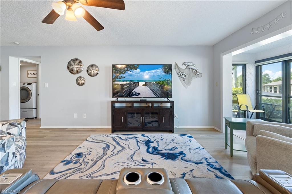 Bright living area featuring wood-finish flooring and a ceiling fan with integrated lighting