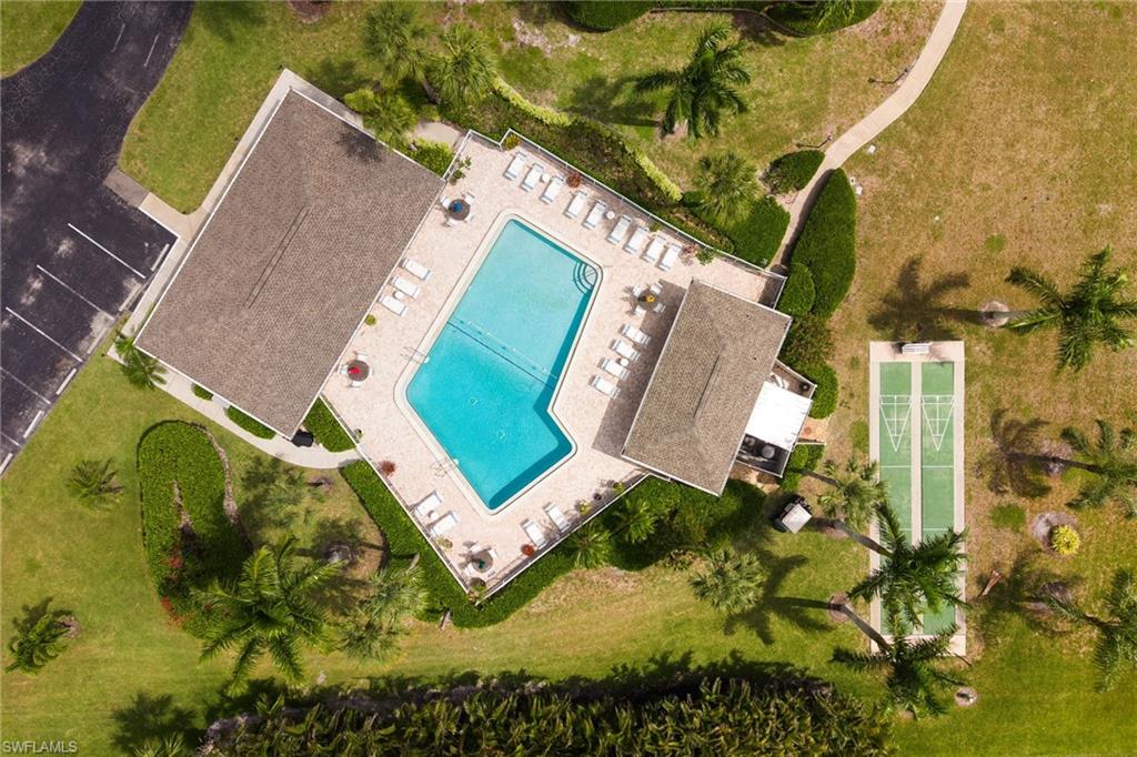 Community amenities featuring a central swimming pool with surrounding patio, clubhouse with a covered outdoor area, dedicated shuffleboard courts, and mature landscaping